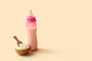 Bir kase toz bebek sütü formülü ve bej arka planda kepçe.