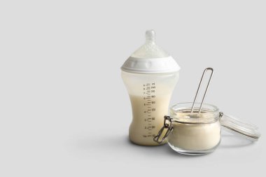 Bir kavanoz toz bebek sütü formülü ve gri arka planda bir şişe