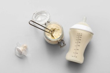 Bir kavanoz toz bebek sütü formülü ve gri arka planda emzik.