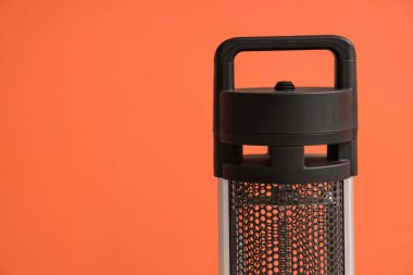 Turuncu arka planda siyah elektrikli fan ısıtıcısı, yakın plan.