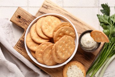 Lezzetli krakerler, otlar ve beyaz fayanslı bir kase sos, yakın plan.