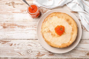 Bej ahşap arka planda kırmızı havyarlı leziz gözlemeler.