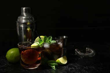 Karanlık arka planda bir bardak lezzetli Küba Libre kokteyli.