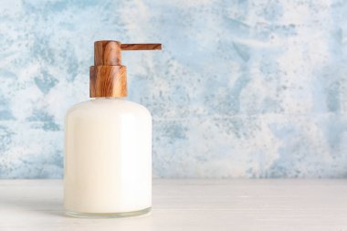 Mavi grunge duvarının yanındaki beyaz masada sabun makinesi.