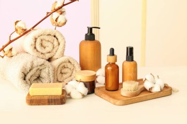 Kozmetik ürünler, banyo malzemeleri ve hafif ahşap masa üzerinde pamuk dalı.