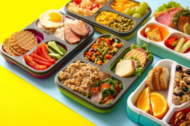 Renkli arka planda farklı lezzetli yemekleri olan birçok beslenme çantası.