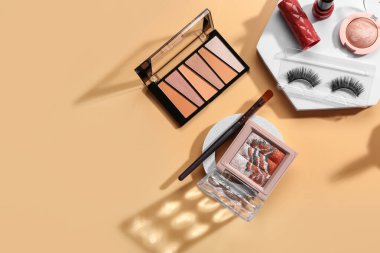 Bej arka planda farklı dekoratif kozmetik ürünleri ile ayakta durur
