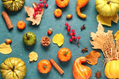 Olgun balkabakları, böğürtlenler, baharatlar ve mavi arka planda düşmüş yapraklarla sonbahar kompozisyonu