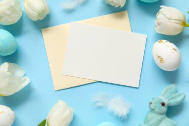 Mavi zemin üzerinde boş kart, lale ve Paskalya yumurtaları olan kompozisyon