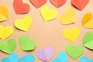 Bej arka planda renkli kağıt kalplerden yapılmış bir çerçeve. Sevgililer Günü kutlaması