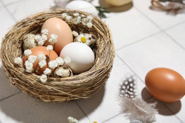 Paskalya yumurtaları, çiçekler ve tüyler beyaz karo arka planda, yakın plan