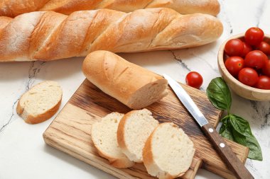 Beyaz arka planda kesilmiş taze baget, fesleğen ve kiraz domatesli ahşap tahta, yakın plan.