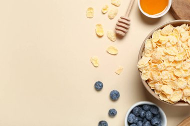 Bej arka planda lezzetli mısır gevreği, yabanmersini ve bal içeren kompozisyon