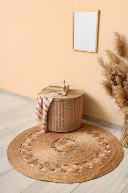 Odada bej duvarın yanında, halıda kitaplar olan bir sepet.