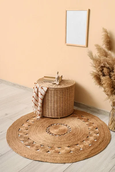 Odada bej duvarın yanında, halıda kitaplar olan bir sepet.