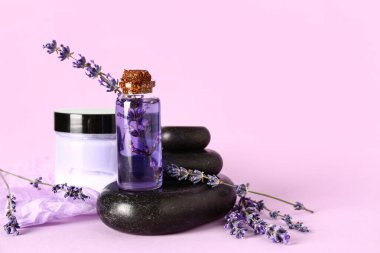 Kozmetik ürünleri, spa taşları ve leylak arkaplanda lavanta çiçekleri olan kompozisyon