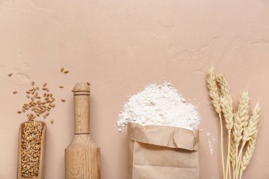 Kahverengi zemin üzerinde buğday unu, merdane, tahıl ve dikenli kağıt torba.