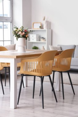 Yemek masasında vazo olan ışık odasının içinde.