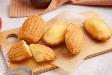 Ahşap tahta tahta, beyaz arka planda fırın kağıdı ve lezzetli madeleine.