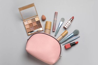 Gri arka planda çantalı dekoratif kozmetik seti. Üst görünüm