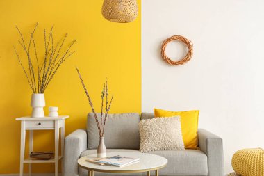 Kanepe, masa ve vazolarda söğüt dalları olan oturma odasının içinde.