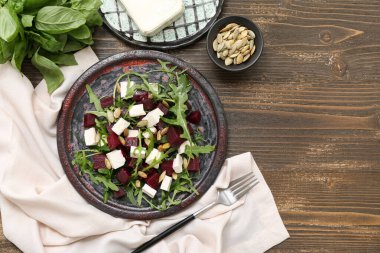 Ahşap arka planda çatal ve peçeteli taze sebze salatası.