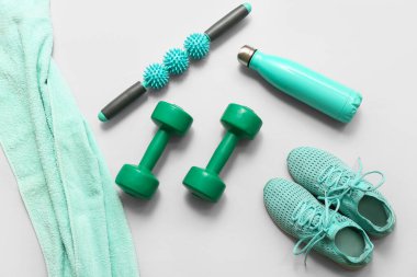 Gri arka planda spor ayakkabıları, havlu ve spor aletleri