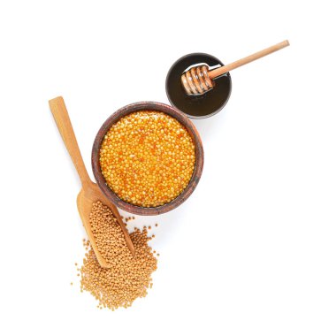 Dijon hardallı ahşap kase ve beyaz arka planda bal.