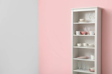 Mutfakta pembe duvarın yanında tabakları olan modern raf ünitesi.