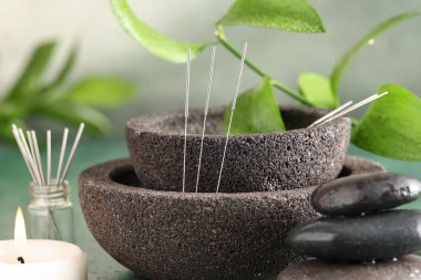 Yeşil zemin üzerinde akupunktur iğneleri, mum ve spa taşları