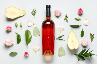 Gül çiçekli bir şişe şarap, armut yarımları ve beyaz arka planda yapraklar