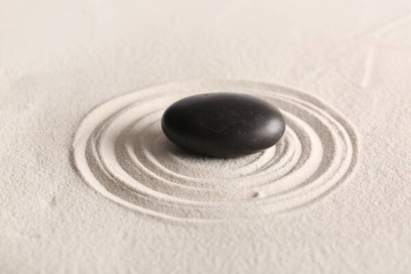 Black stone on light sand with lines. Zen concept