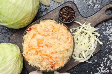 Bir kase lezzetli mayalanmış lahana ve siyah masada malzemeler. Yakın çekim.