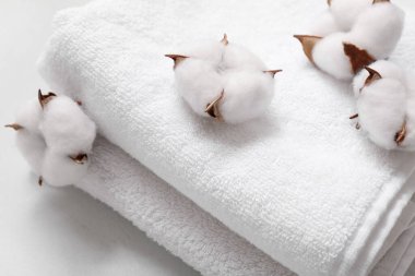 Temiz havlu yığını ve arka planda pamuk çiçekleri, yakın plan
