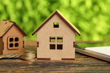 Dışarıdaki masada para ve hesap makineli ev figürleri, yakın plan. Fatura ödemesi kavramı