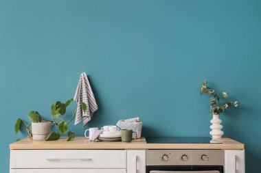 Mavi duvarda asılı temiz havlu ve mutfakta bir sürü bulaşık.