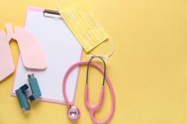 Astım spreyleri, kağıt ciğerler ve sarı grunge arka planda steteskop olan bir pano.