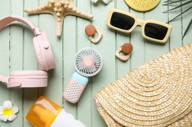 Kulaklıklı kadın aksesuarlar ve yeşil ahşap arka planda mini vantilatör.