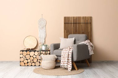 Ahşap masa ve bej duvarın yanında katlanır ekran ile yumuşak gri koltuk