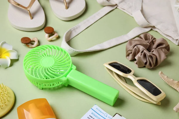 Yeşil arka planda kadın yaz aksesuarları ve mini fan.