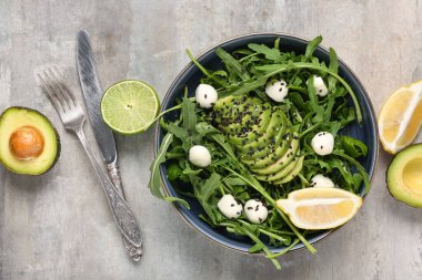 Lezzetli roka salatası ve gri grunge arkaplan içerikli kase, yakın plan.