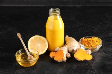 Bir şişe sağlıklı zerdeçal içeceği ve siyah grunge arkaplan malzemesi.