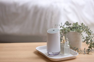 Yatak odasındaki masada gerekli yağ ve bir tencere okaliptüs içeren hava nemlendirici.