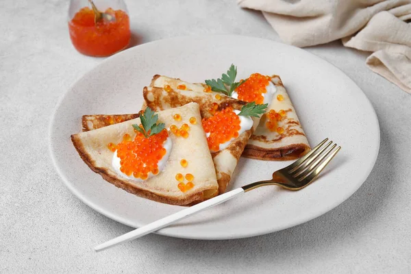 Kırmızı havyarlı leziz gözlemeler ve gri arka planda ekşi krema.