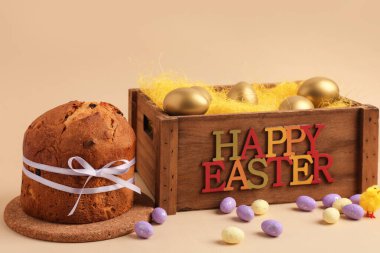 Lezzetli Paskalya pastası, boyalı yumurta ve bej arka planda ahşap kutu.