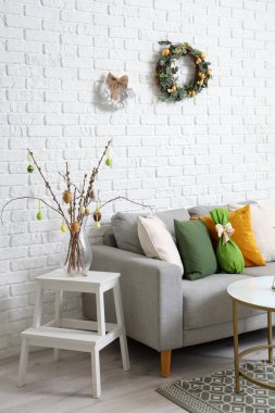 Paskalya çelenkleri ve kanepesi olan bir oturma odası.