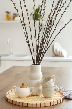 Mutfaktaki masada söğüt dalları ve fincanları olan vazo, yakın plan.