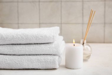 Beyaz arka planda temiz yumuşak havlular, mum ve aroma çubukları ile güzel kompozisyon, yakın plan