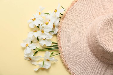 Güzel nergis çiçekleri ve sarı arka planda hasır şapka