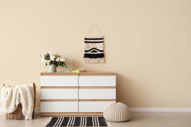 Çağdaş çekmecelerde bej duvarın yanındaki odada leylaklar olan vazo.